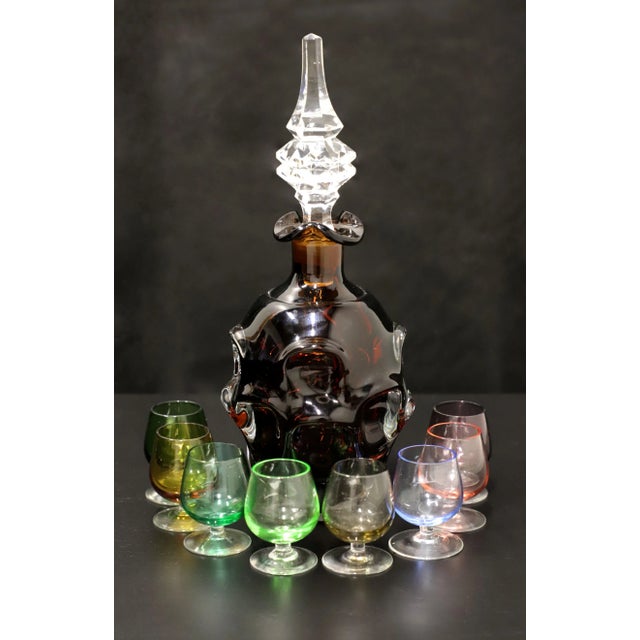 A Mid 20th Century amber glass decanter with stopper and eight various color cordial glasses. Amber glass decanter with...
