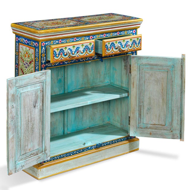 A stunning hand-painted wooden cabinet showcasing authentic Indian folk art traditions. Adorned with intricate floral...