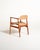 Teak frame with light proportions, contoured armrests, and beige faux leather upholstery on the seat and back....