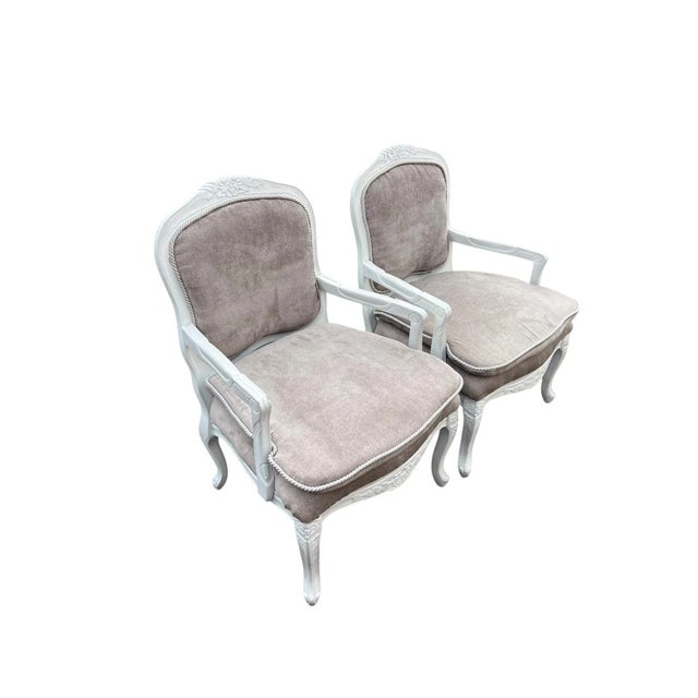Pair of elegant French chairs with carved frames and soft, neutral taupe-gray velvet upholstery with white rope trim....