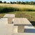 Gorgeous set of two square travertine side tables, each resting on a single center pedestal. Each tabletop features rough...