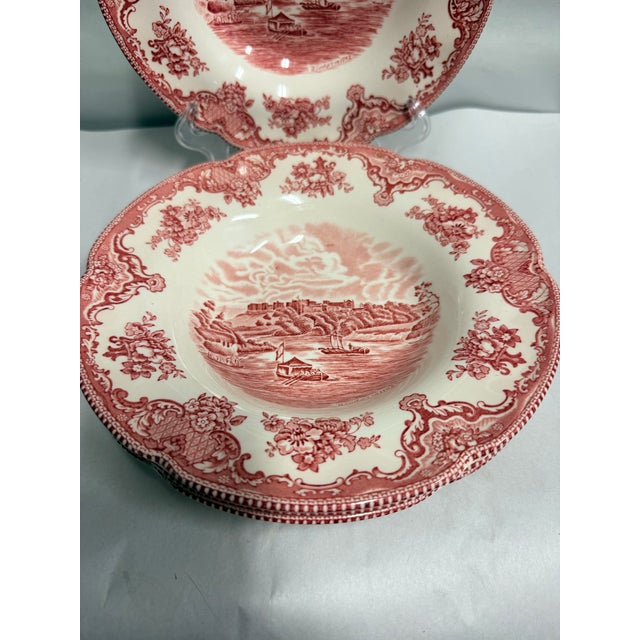 This set includes four vintage Johnson Brothers soup bowls featuring a classic red transferware design depicting a scenic...