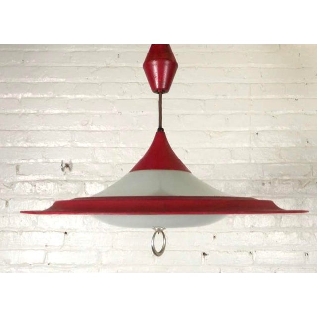 This stunning mid-century modern vintage hanging light pendant features a striking enameled red metal shade paired with an...