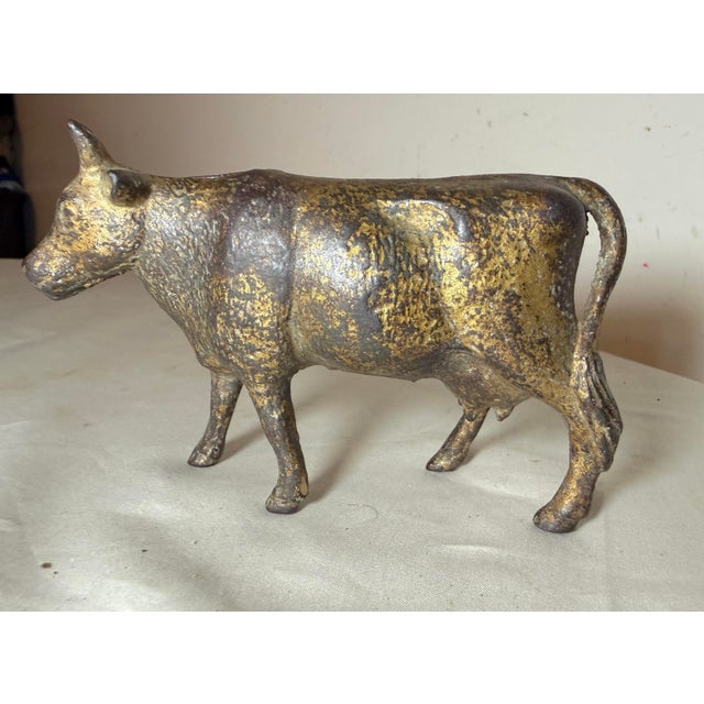 This Antique 1920's Cast Iron Gold Cow Still Bank by A.C. Williams is a unique and collectible piece with an exquisite...