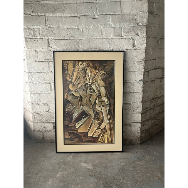 Own a piece of art history with this beautifully framed reproduction of Marcel Duchamp's iconic Nude Descending a...