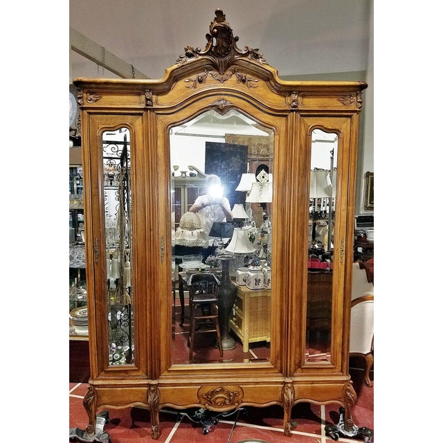 So classic of the Belle Epoch, this solid hand carved French walnut L. XV style 3 door armoire arranged as a hanging...