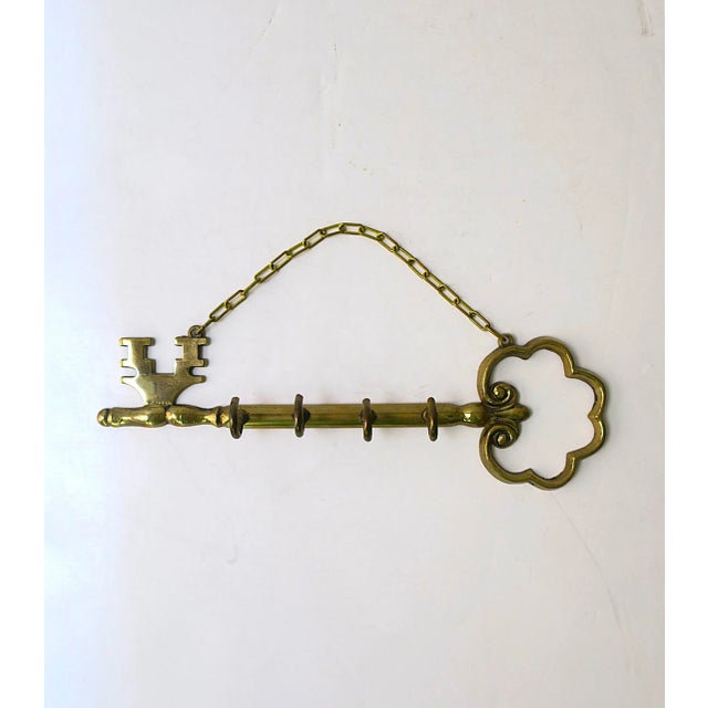 A brass wall key 'key' holder, circa mid-20th century. This brass wall key holder is designed in the shape of an antique...
