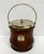 Imported from England. Classic oak biscuit barrel with porcelain liner. Silver rim, handle, cover, and crest labeled...