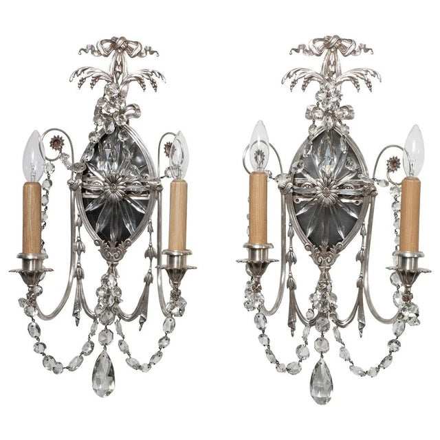 Pair of large silvered bronze sconces featuring a foliate motif, cut crystal elements and original ceramic candle covers.