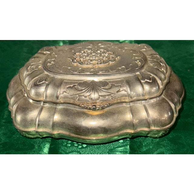 Beautiful vintage-style silver-tone decorative trinket box featuring an ornate raised floral design and scalloped edges....
