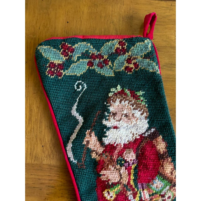 Classic 1990s Christmas stocking made in wool needlepoint, red velvet back and cording. The needle work depicts a pipe-...