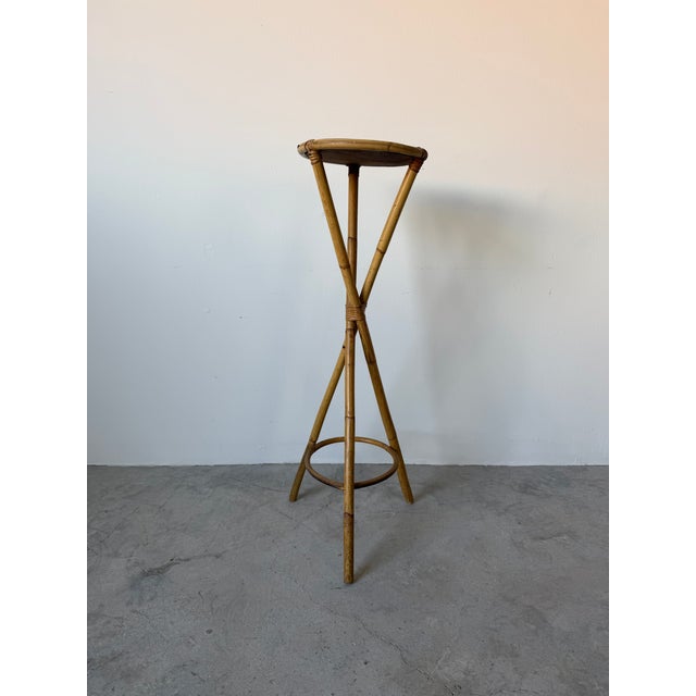 Beautiful vintage coastal pedestal stand crafted from natural bamboo and rattan, featuring a sculptural tripod base with...