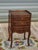 Elegant bedside table with three drawers and raised edges on three sides of the top. Tall, slender legs with cabriole...