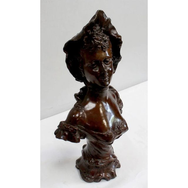 Bronze bust with brown patina signed Meslais, representing and elegant damsel wearing a hat over her wavy hair. Her air...