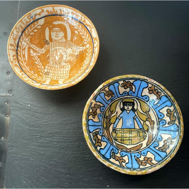 A collection of two small pottery bowls with polychrome central figurative decorations, matching size and similar conical...