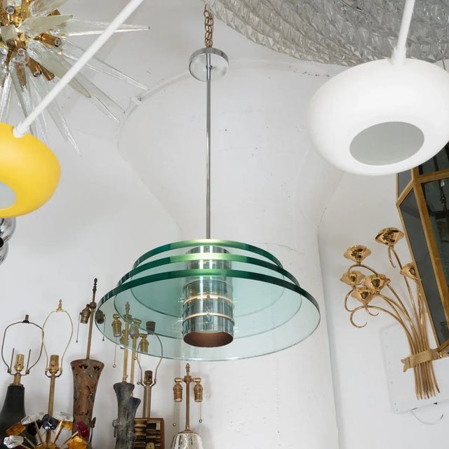 Space age polished nickel and glass pendant with stacked glass disks at center. Arrangement of glass disks can be changed.