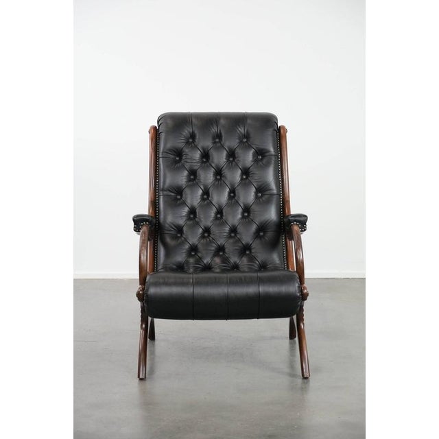 Offered by Thijs: this luxurious, classic, and comfortable black cowhide Chesterfield armchair in good condition with...