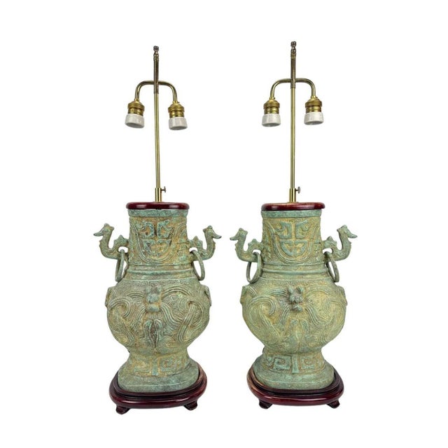 A pair of bronze chinoiserie lamps with verdigris patina, dragon handles and rosewood base. The hu form vessel lamp is a...