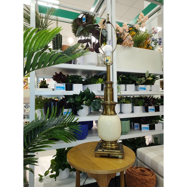 Hollywood Regency brass table lamp by Stiffel, featuring a cream colored porcelain "ostrich egg" body. Heavy brass square...