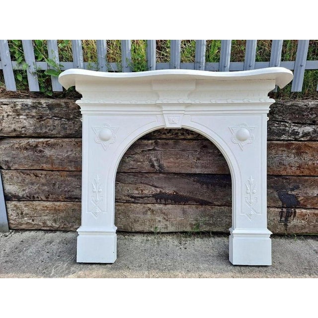 A handsome antique victorian cast iron arched fireplace surround, distinguished by its elegant architectural form,...