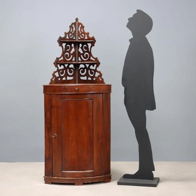 Half-moon walnut corner cabinet, central door and drawer under the top, perforated top with two shelves. Bracket legs....