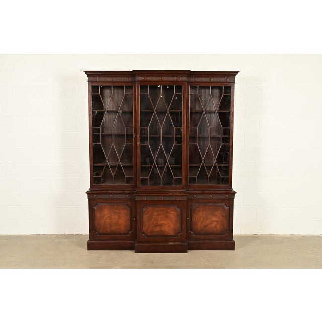 A gorgeous Georgian or Chippendale style breakfront bookcase or dining cabinet By Baker Furniture USA, Circa 1960s Carved...