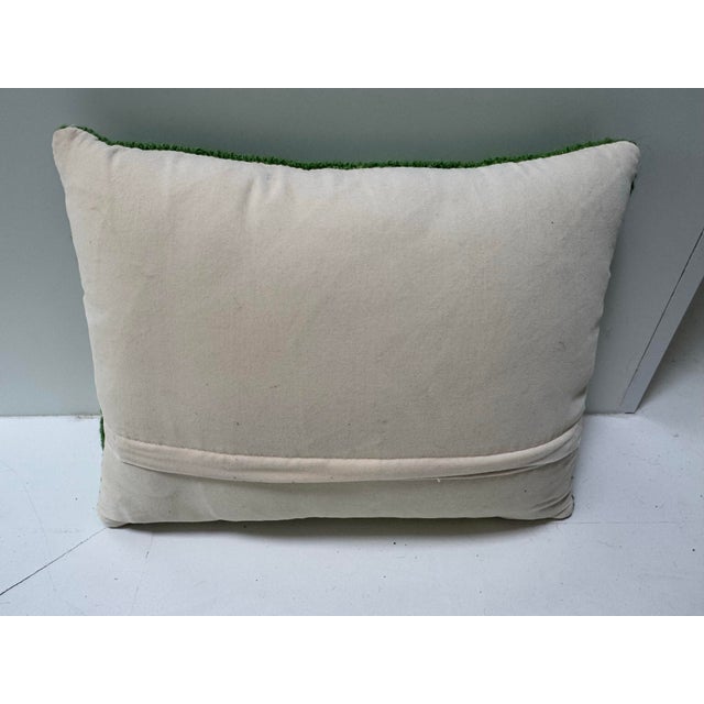 A spring green hooked pillow with Libra astrological sign.