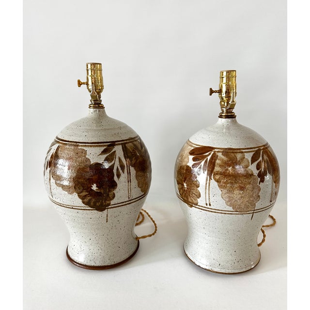 Pair of 1970s hand thrown stoneware lamps with floral pattern. Hand crafted with variations between each lamp. Newly wired...