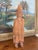 This hand-carved folk art wood sculpture depicts a bearded man wearing a wide-brimmed hat and long cloak, carrying a small...