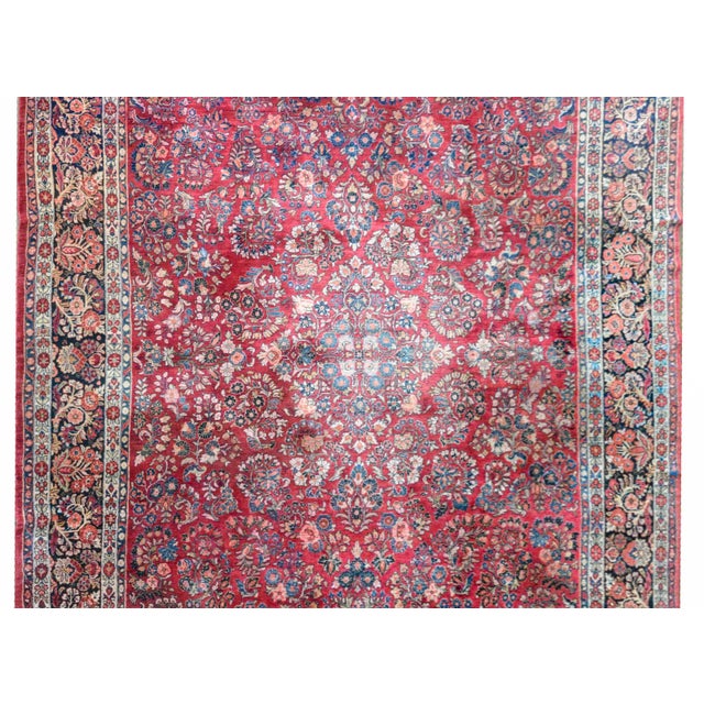 A early 20th century Persian Sarouk rug with a traditional pattern containing myriad clusters of flowers woven in light...