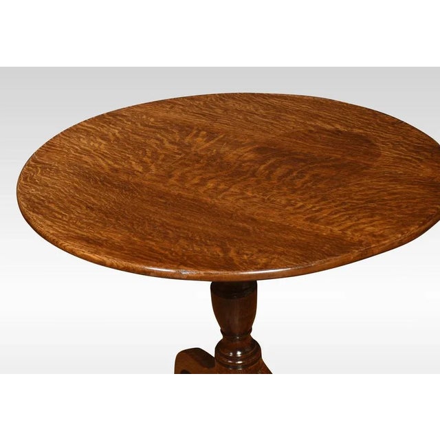 Oak tripod table, the circular top above the ring-turned pedestal. All raised up on three down-swept supports terminating...