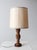 This vintage table lamp features a rounded wooden base and a richly carved column adorned with floral motifs. The warm...