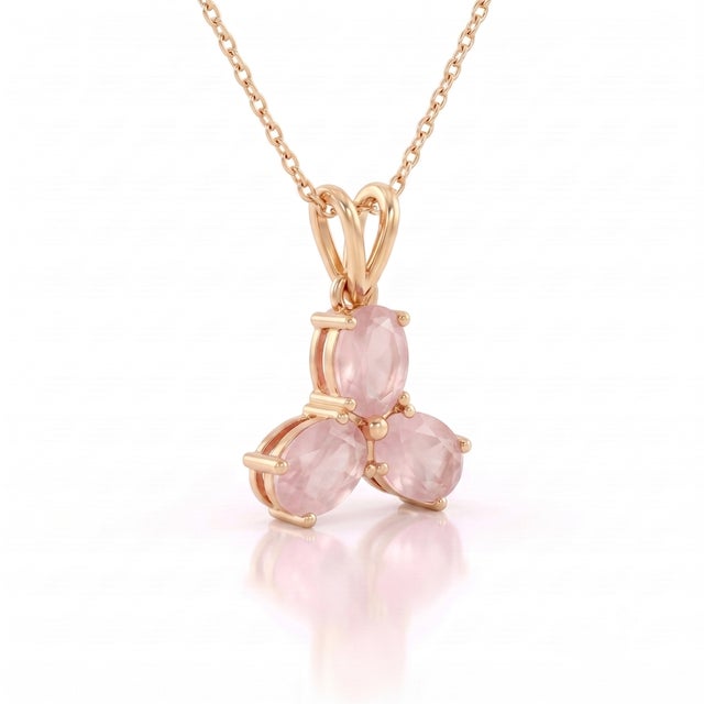 A romantic three-stone design featuring oval-cut natural rose quartz arranged in a graceful trefoil formation, secured in...