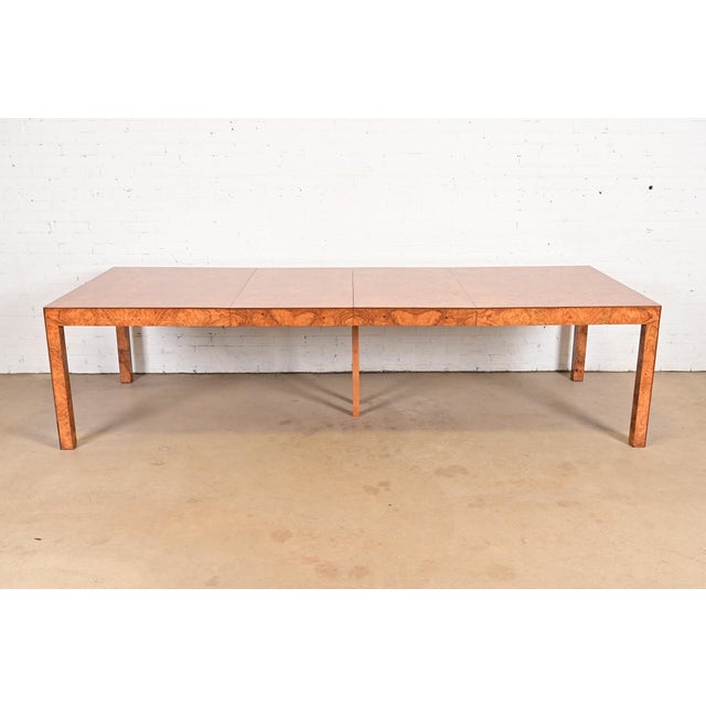An outstanding Mid-Century Modern Parsons extension dining table in gorgeous book-matched burl wood In the manner of Milo...