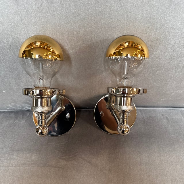 Design Plus Gallery presents a Pair of Bistro Globe Wall Sconces. The polished steel pair were inspired by 1940's...