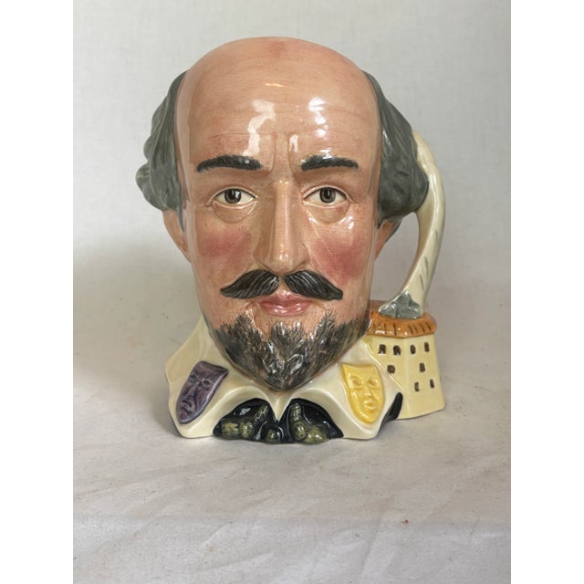 This Royal Doulton Toby jug depicts William Shakespeare. The jug has a feather form handle with a building below. His...