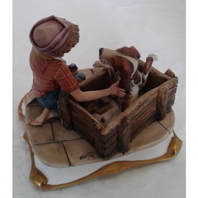 A charming, highly detailed vintage hand-painted Italian Capodimonte porcelain figurine depicting a young boy kneeling...