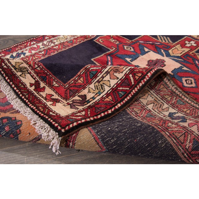A beautiful Vintage Heriz Handmade Wool Rug with a red field and multicolor accents in allover geometric medallion design....