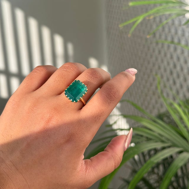 This striking 9.08-carat emerald-cut emerald solitaire ring is crafted in 18K yellow gold. The emerald, measuring about 15...
