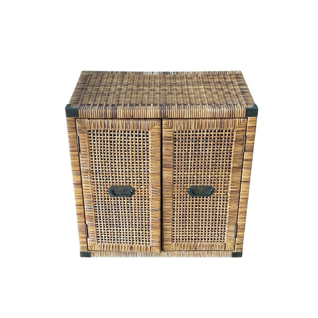 This is a compact vintage wicker cabinet, likely mid-20th century, crafted in warm honey-toned rattan or reed over a wood...