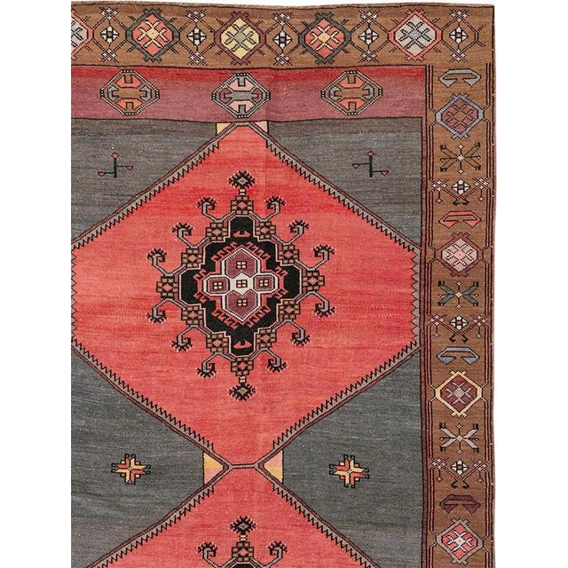 This Mid-20th century Turkish Anatolian room-size carpet presents a bold twin-panel composition arranged across coral-red...