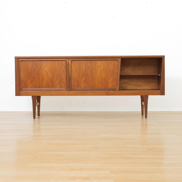 This mid-century credenza was produced by Elliots of Newbury the 1960s. Featuring distinct sliding doors, with two large...