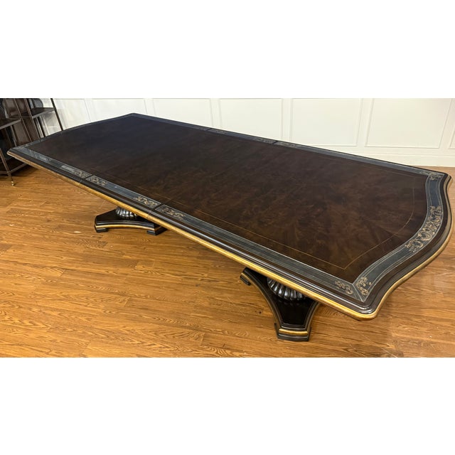This is the Grand Traditions Dining Table by Maitland - Smith. It features a mahogany top with a field of beautifully...