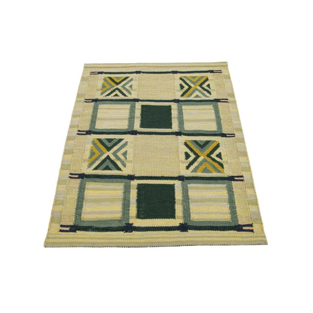 This Swedish flatweave rug showcases a contemporary Swedish design with a beige-yellow base. It's accented with green...