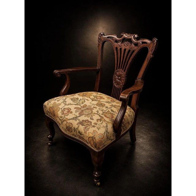 An elegant late 19th-century mahogany open armchair distinguished by its finely carved and pierced back, graceful...