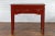 A vintage Chinese red lacquered console table from the mid 20th century, with three drawers, waisted top, carved spandrels...