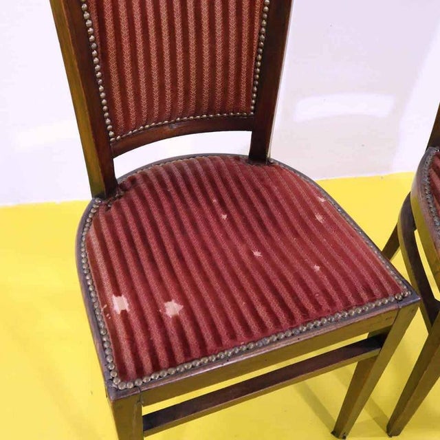 Pair of wooden chairs featuring red upholstery and decorative studs.