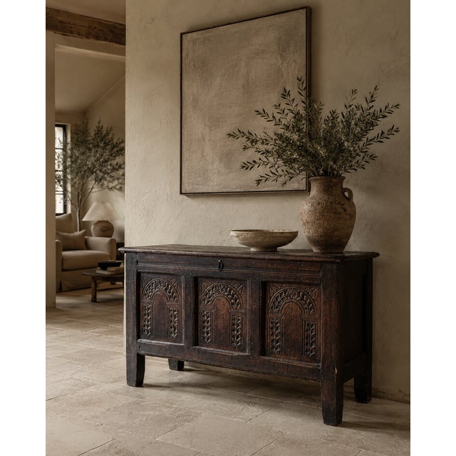 A characterful 17th century English joined oak coffer, dating to approximately 1650–1700, with a richly carved three-panel...
