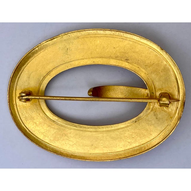 A handsome antique bright gold gilded brass buckle brooch with raised flourish designs on two sides.
