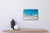 This artwork presents a serene aerial view of a white sand beach, where vibrant turquoise waves gently meet the shore. The...